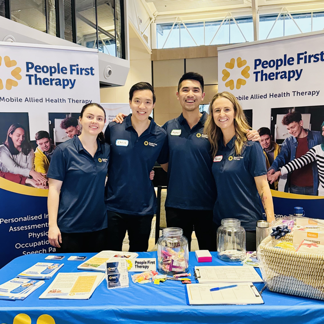 The People First Therapy team smiling and posing for a photo at a corporate booth