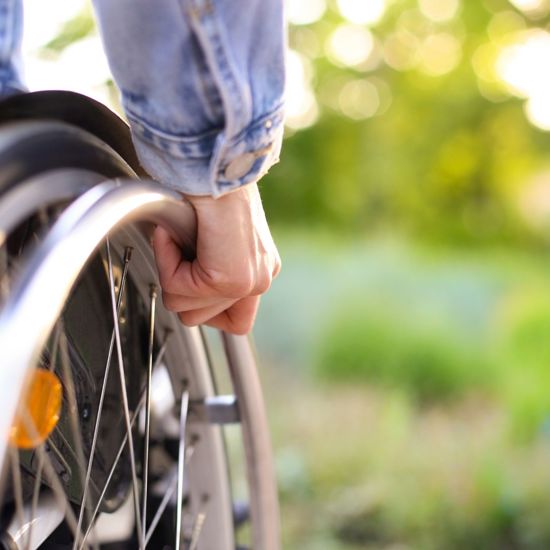 A persons hand on the wheel of a wheelchair