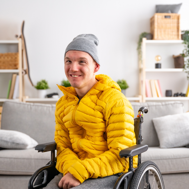 Man in wheelchair wearing a yellow jacket and a beanie