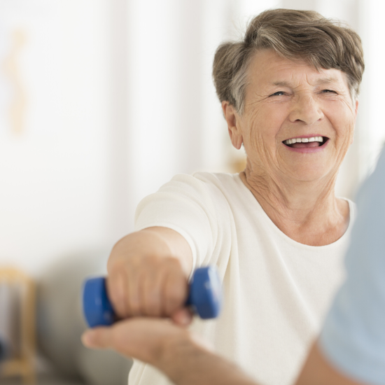 Elderly female exercising and smiling with physiotherapist