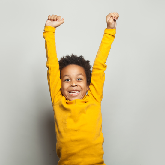 Young boy with raised hands wearing a yellow jumper