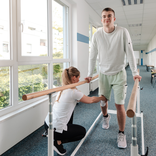 Female caregiver helping a young male with physiotherapy on his leg